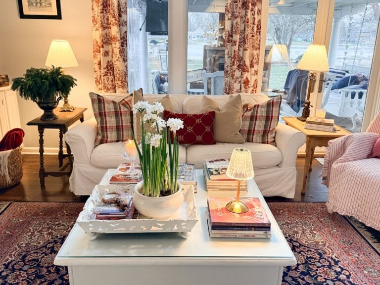 Cozy living room with a white sofa, plaid pillows, and floral curtains—perfect for Christmas in July holiday season planning.