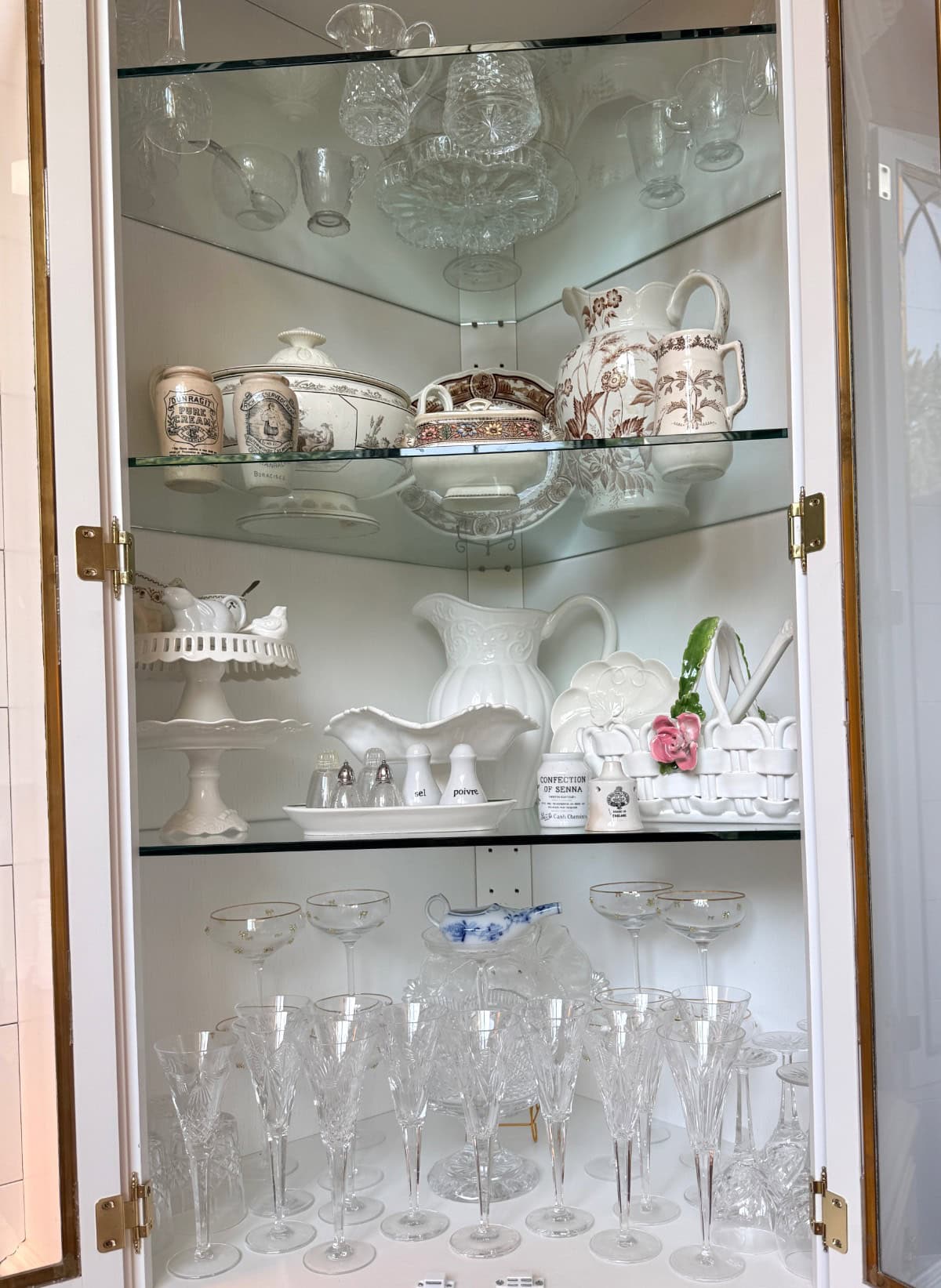 Glass cabinet for elegant home organization, displaying crystal glasses, teapots, dishes, and decor on three shelves.