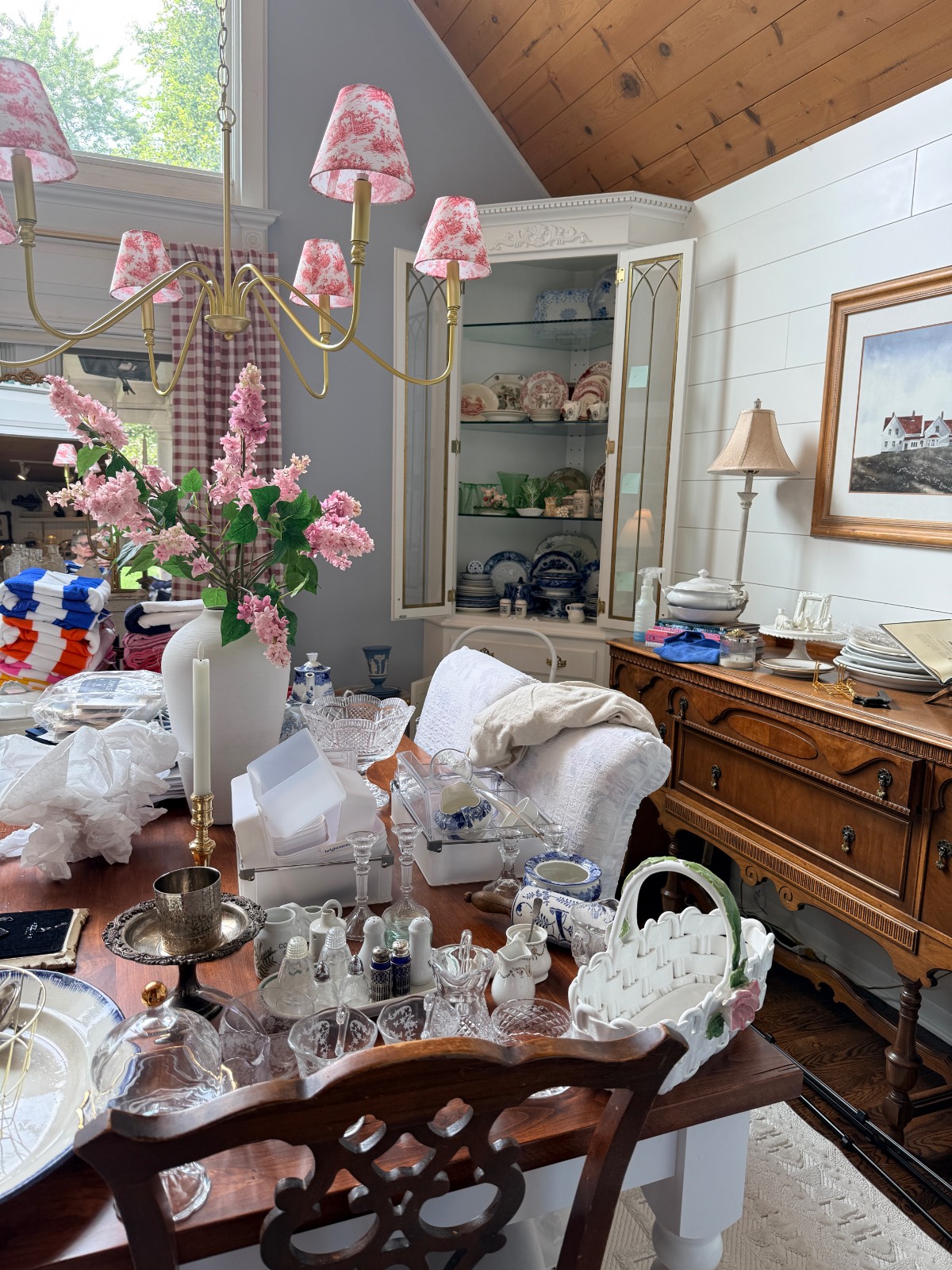 A dining room with the latest vintage dishes, glassware, and floral decor arranged on the table and sideboard.