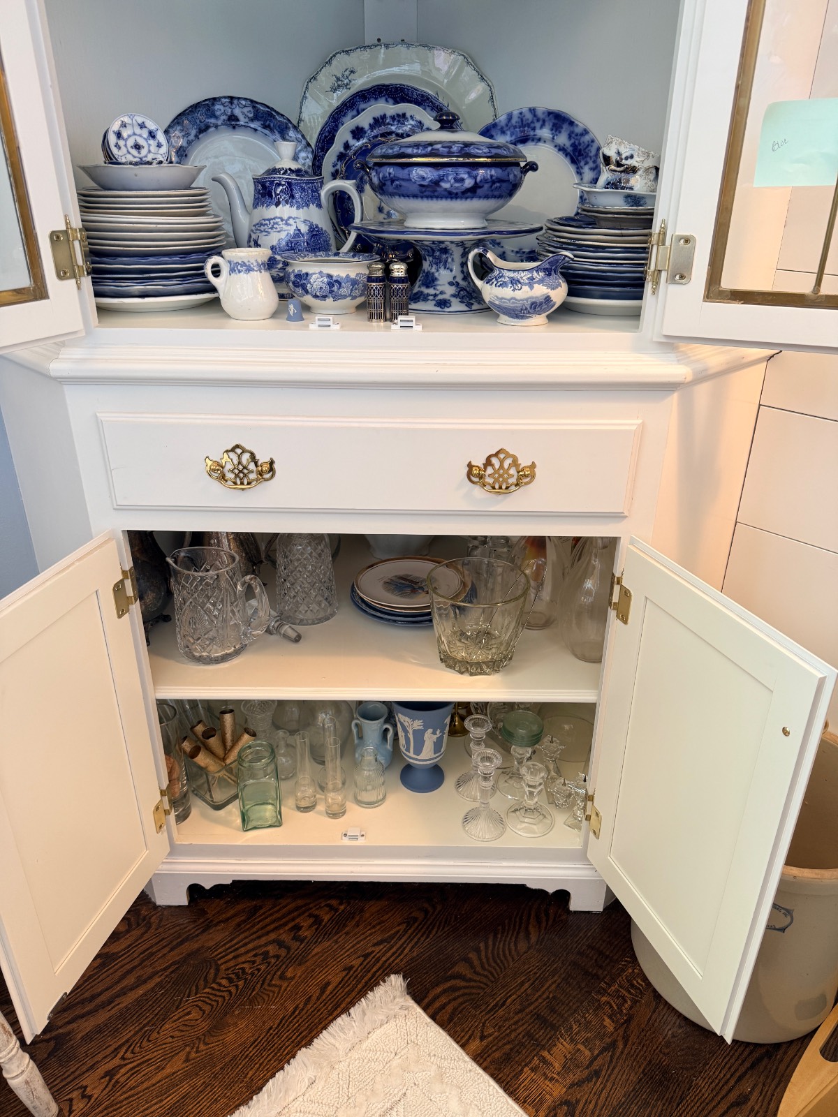 White cabinet after a closet makeover, doors open to display blue china, glassware, and vintage dishes on shelves.