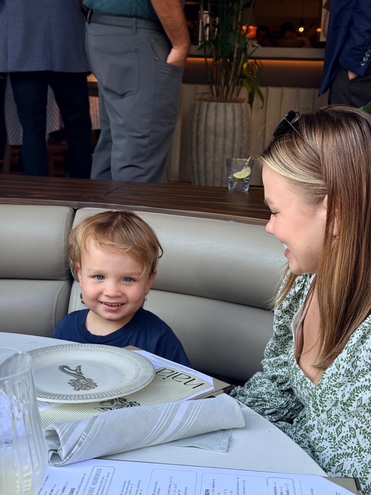 A smiling child sits at a restaurant table with a woman, both enjoying the latest dishes and looking happy and relaxed.