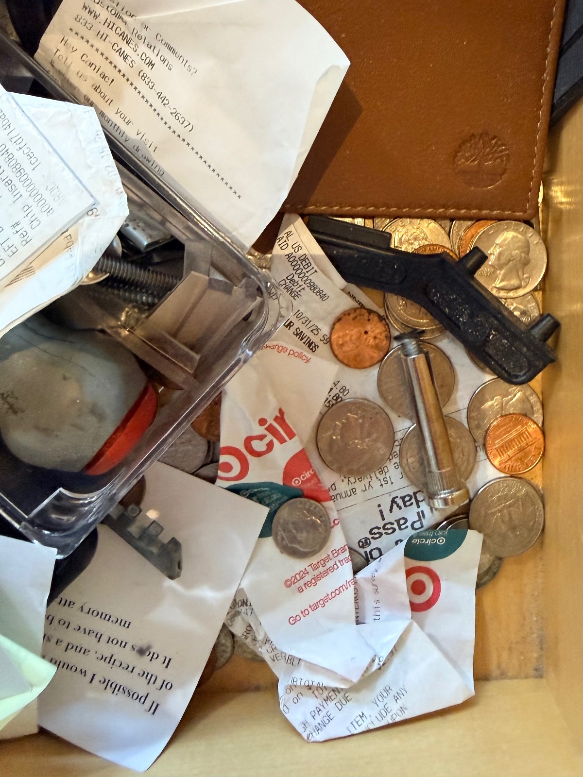 Drawer with coins, receipts, a black key, and things to throw away right now scattered among small items.