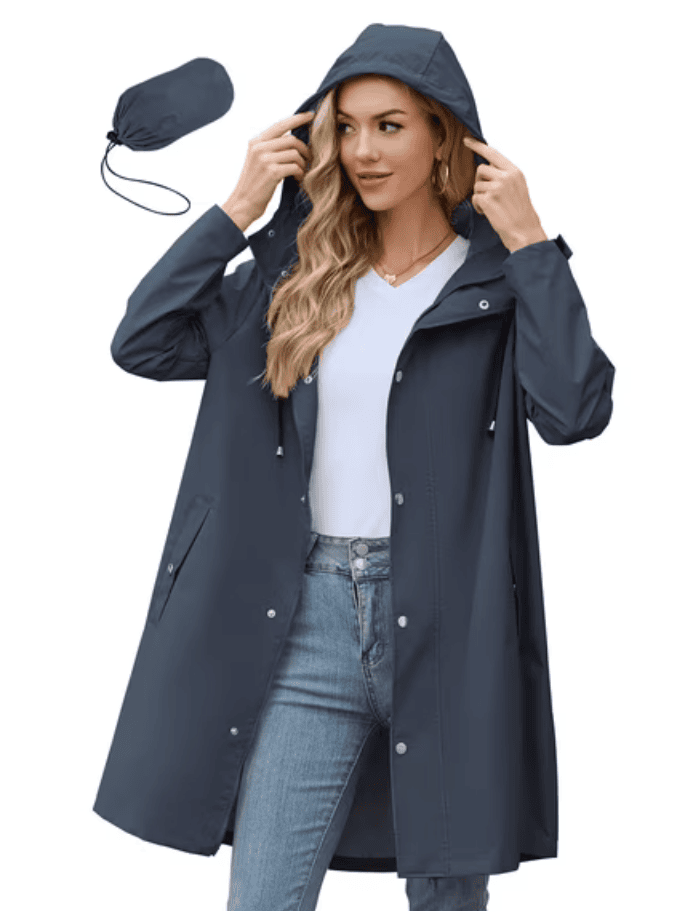 Woman in a dark blue raincoat with hood, perfect for shopping, jeans and white top, matching pouch also shown.