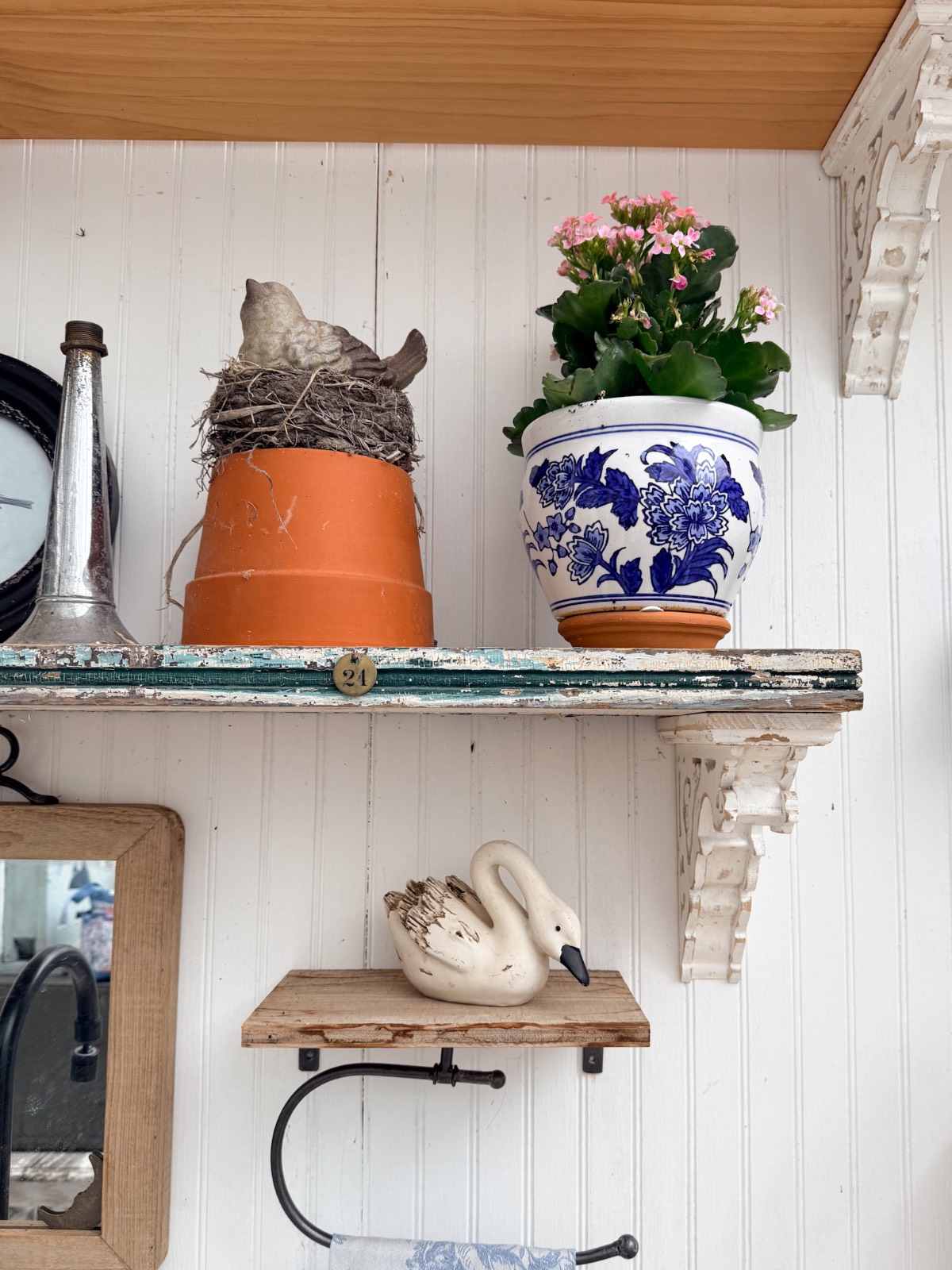 A plant in a blue floral pot, vintage finds, and a swan figurine bring summer styling to rustic shelves.