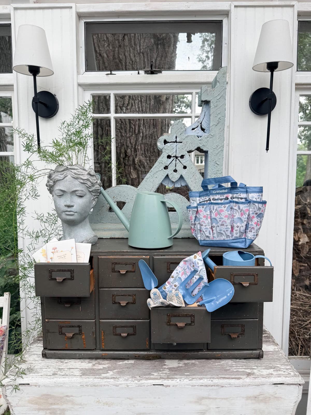 Vintage finds: drawers with garden tools, a bust, gloves, and cards create effortless summer styling by the window.