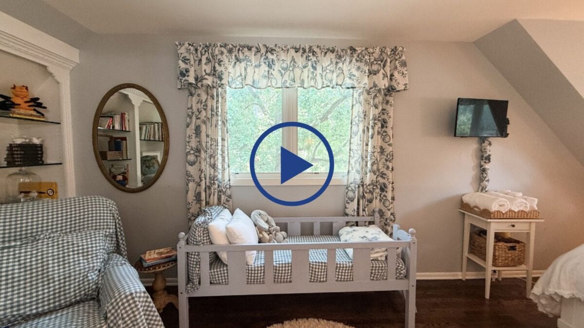 Cozy nursery doubles as a guest room makeover, featuring a small bed, patterned curtains, bookshelves, and a TV.