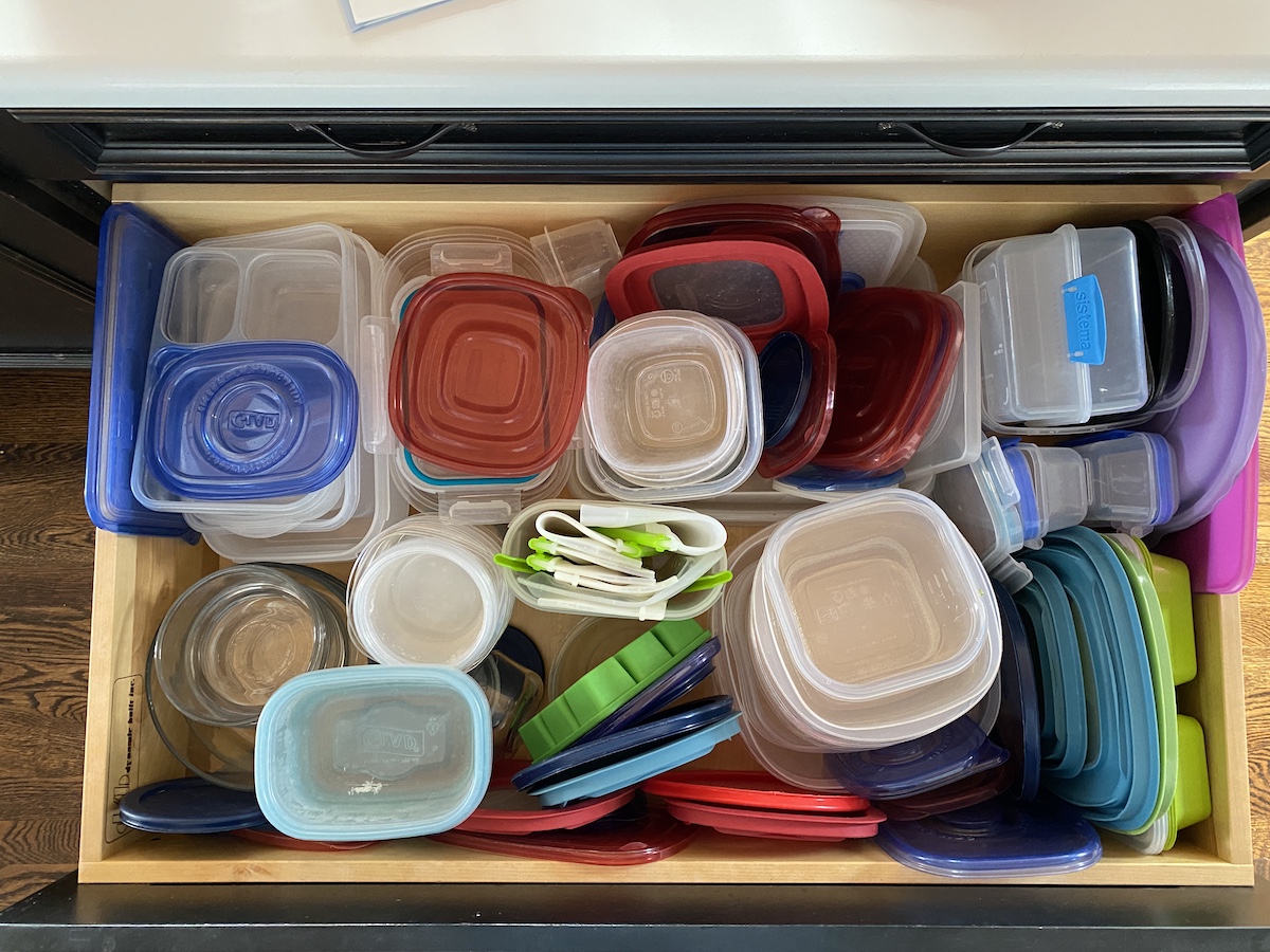 A kitchen drawer filled with assorted plastic food containers and lids—some of which are things to throw away right now.