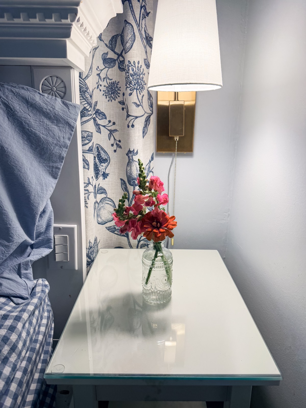 A glass jar with colorful flowers adds a cozy touch to the bedside table in this inviting family suite.