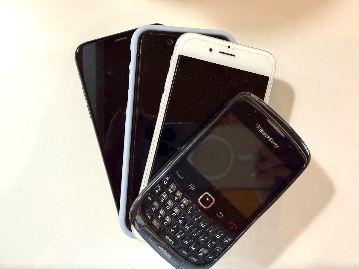 Four old smartphones stacked, BlackBerry on top—classic examples of things to throw away right now.