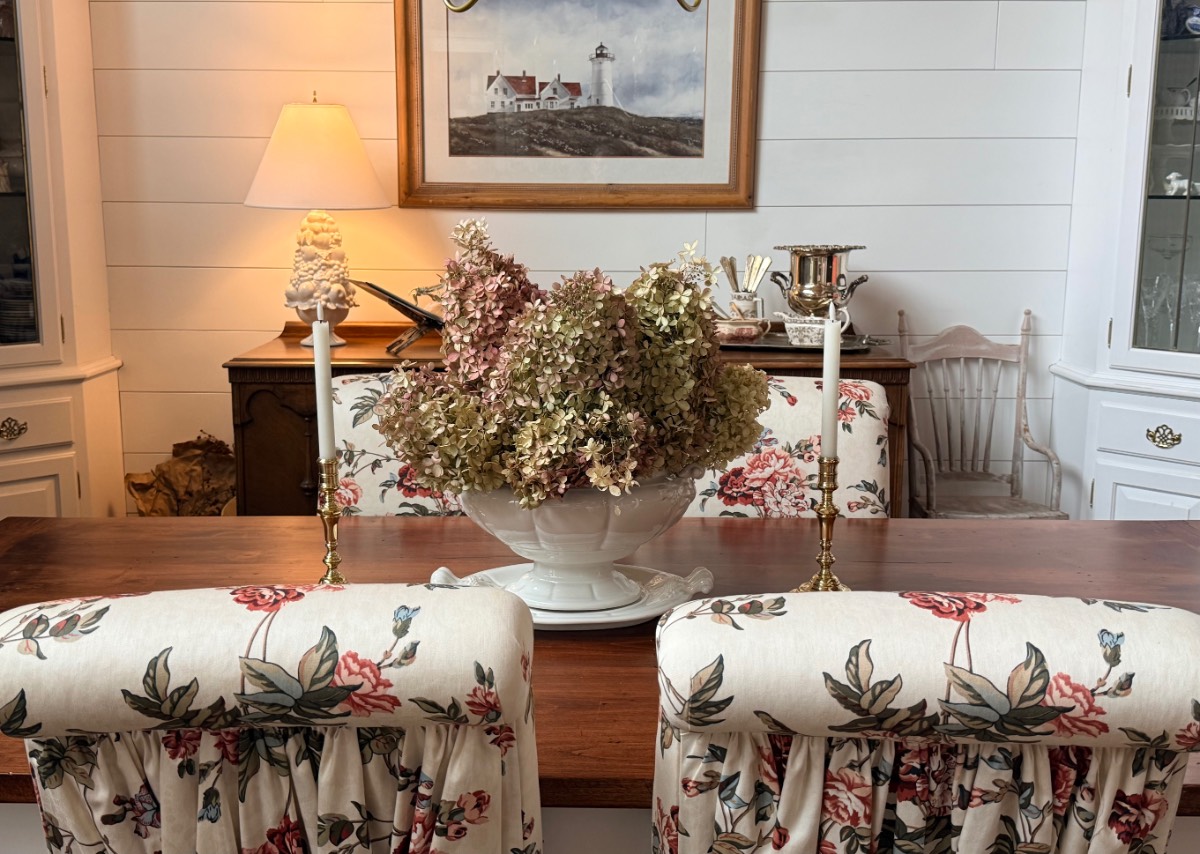 Vintage ironstone tureen filled with dried hydrangeas between brass candlesticks