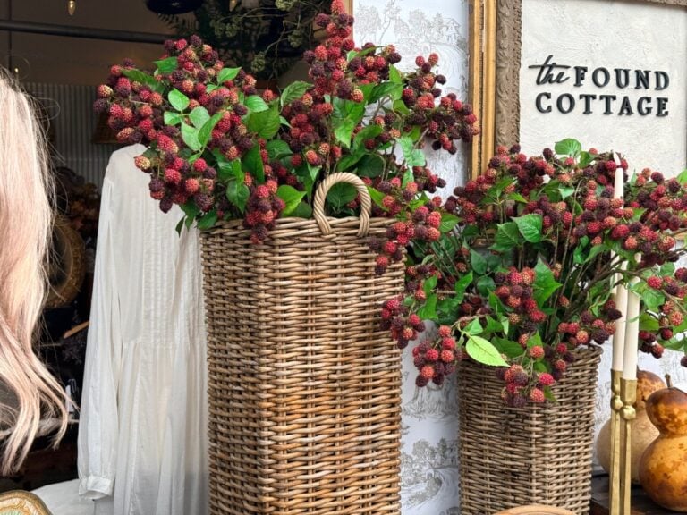 Two wicker baskets display the latest faux berry branches outside a shop with a “the Found Cottage” sign.