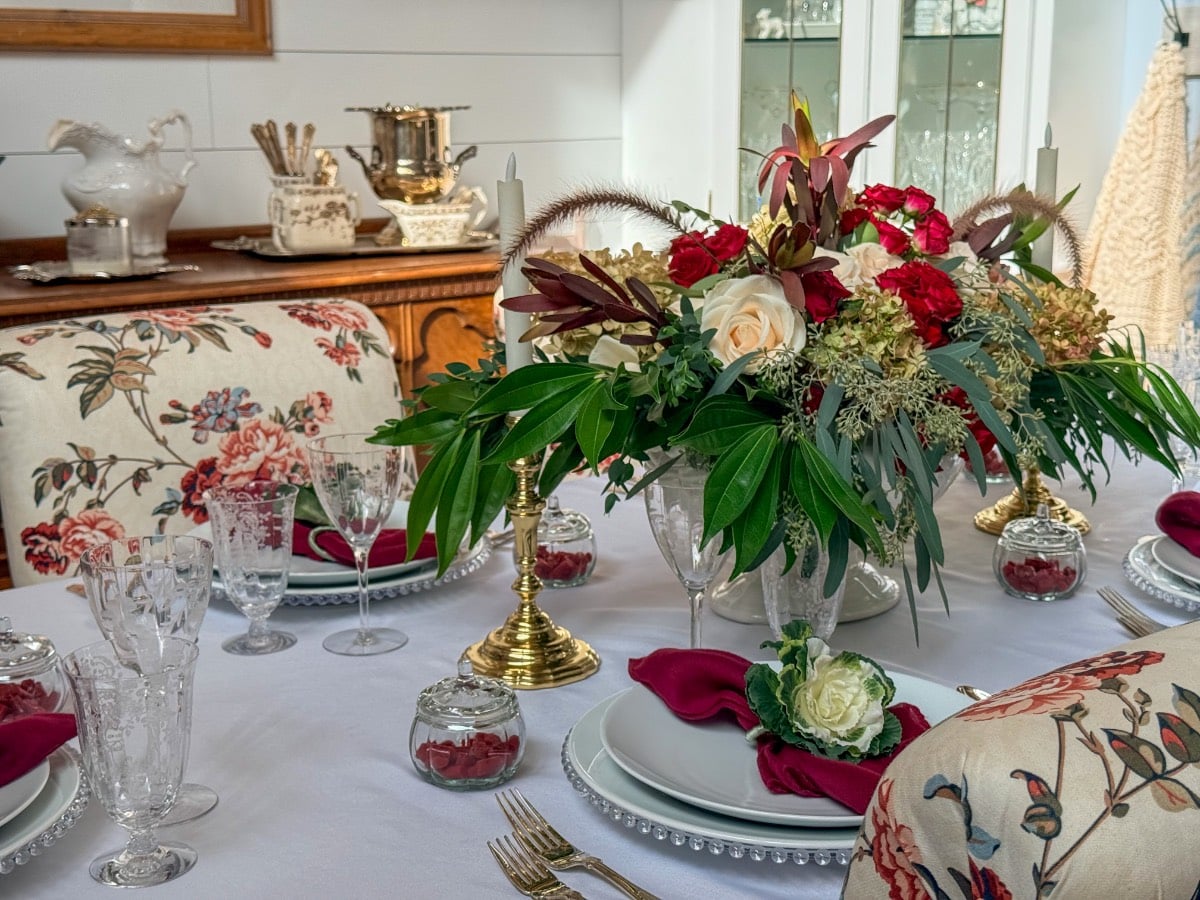 A formal dining table set with white plates, red napkins, and a floral centerpiece, perfect for Thanksgiving hosting.