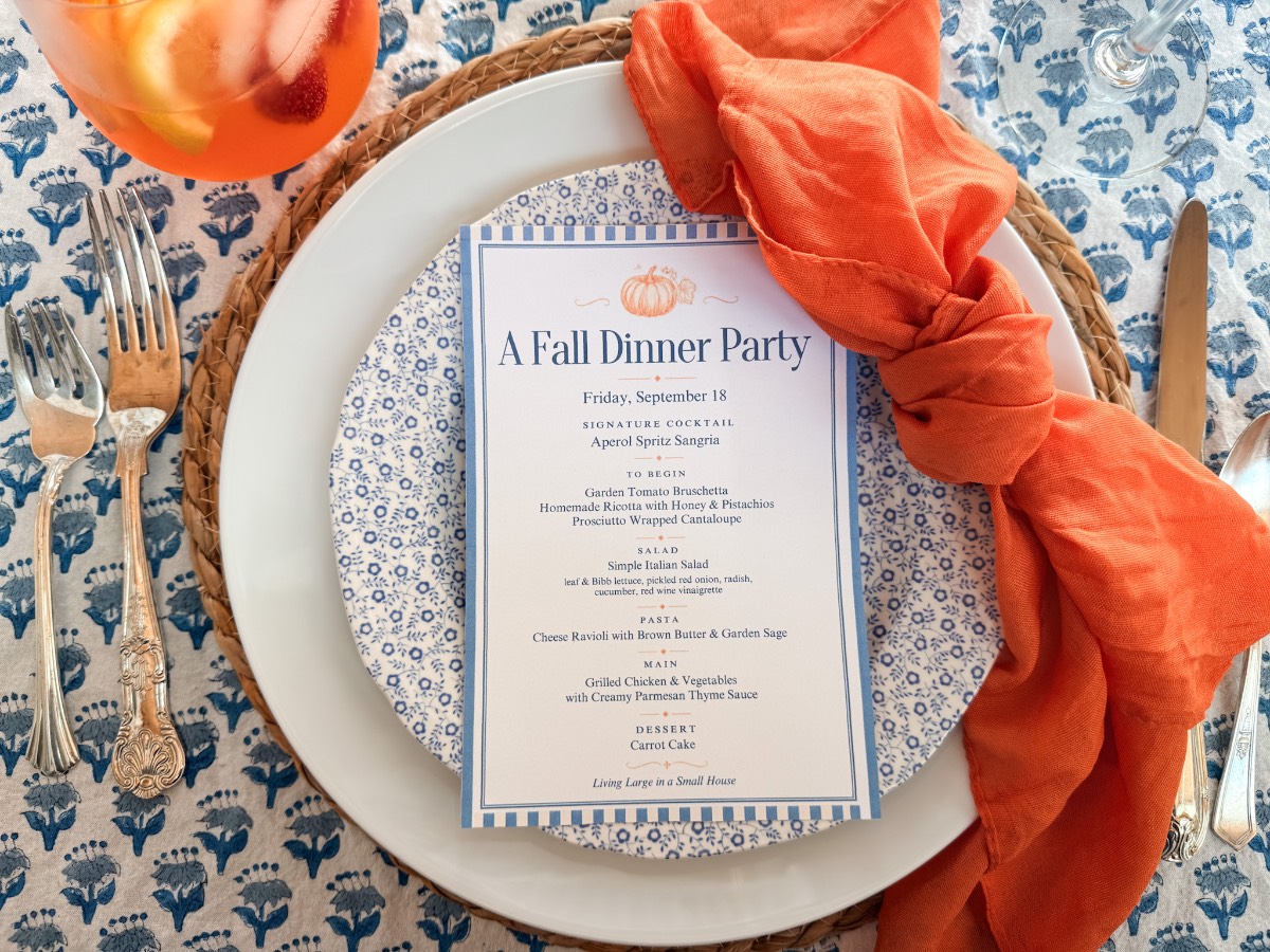 An A Fall Dinner Party menu on a floral plate with an orange napkin, perfect for an outdoor fall dinner party.